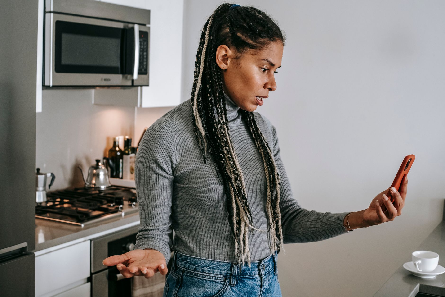 A concerned person holds a smartphone showing a video call, looking at the screen.