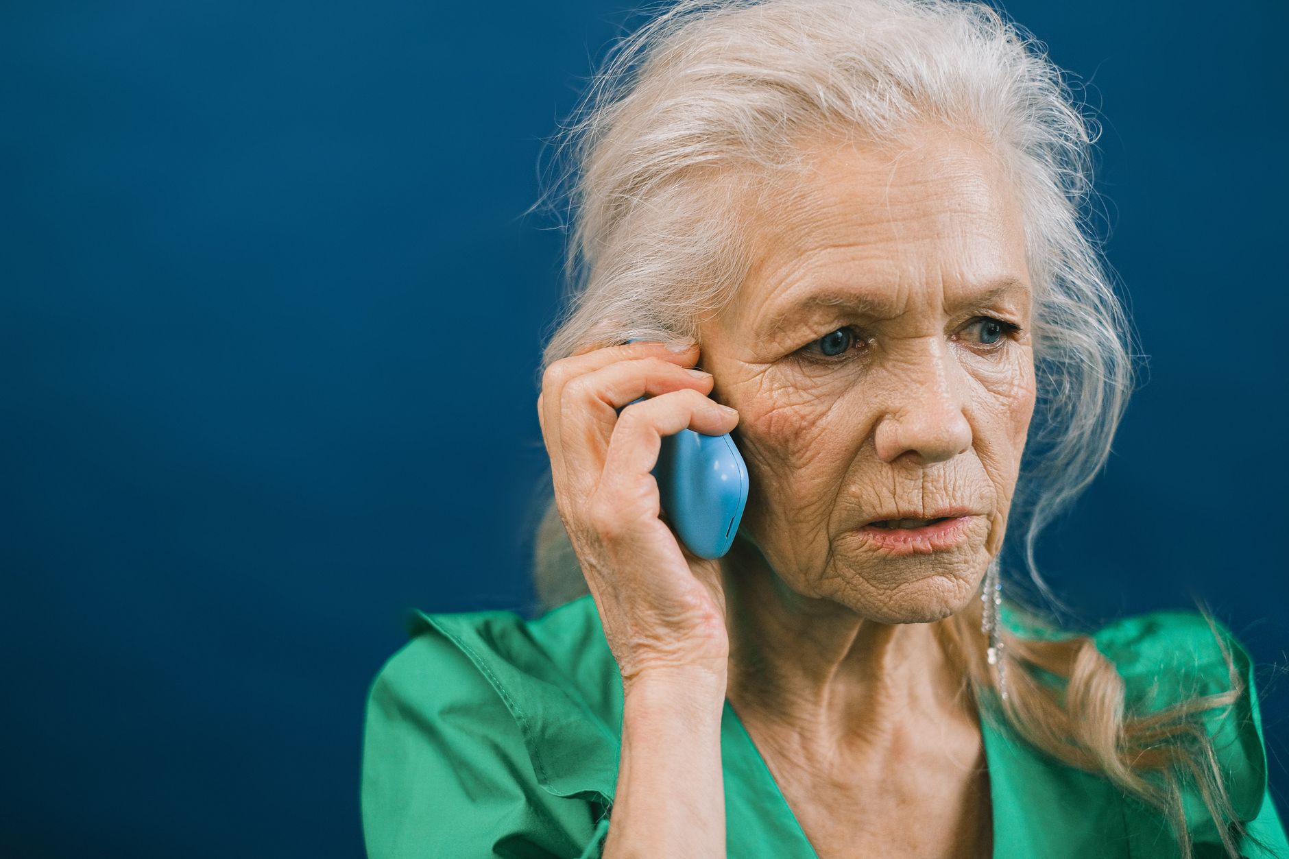 An older adult looking at a smartphone with a worried expression