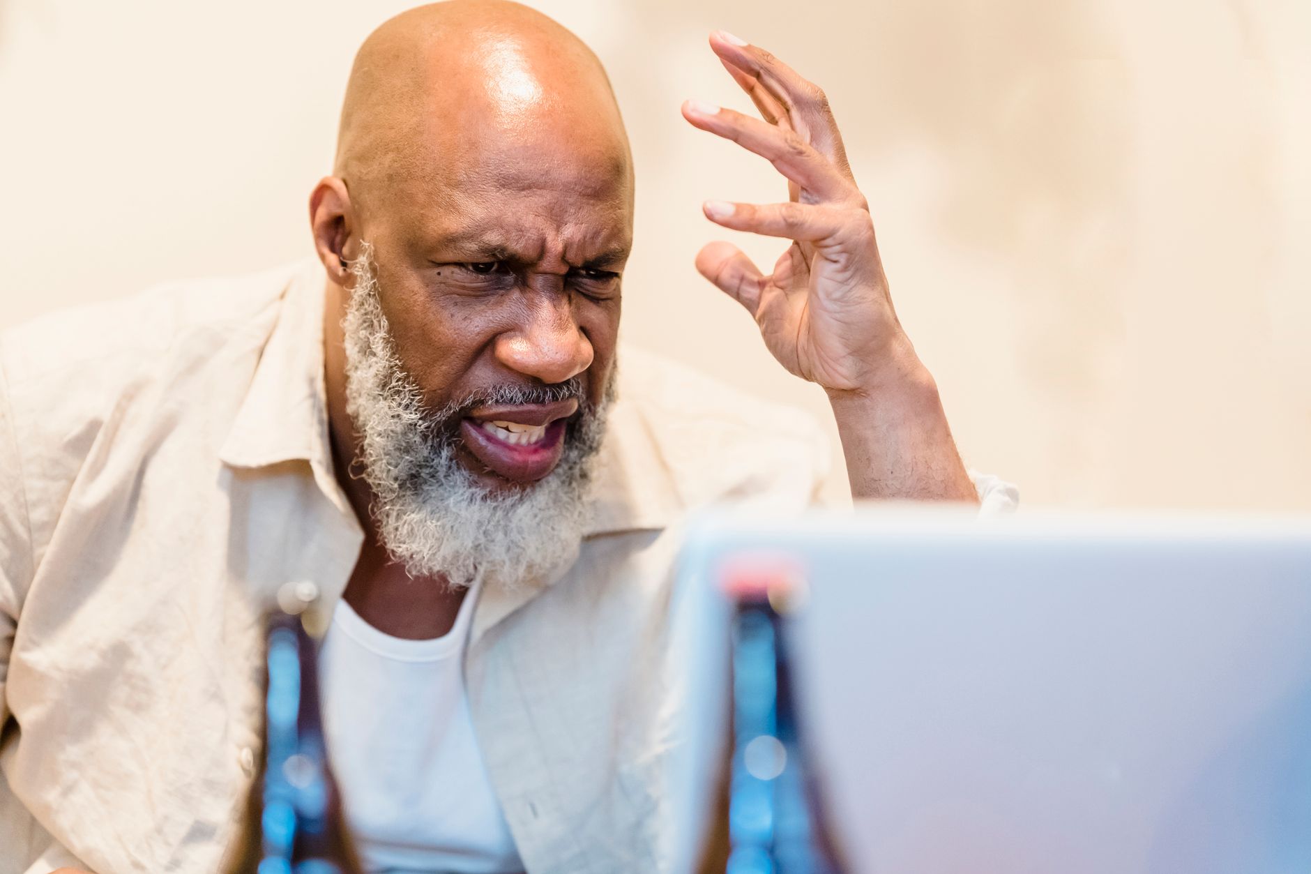 A person frowning slightly while reading an email on a laptop in a bright room.