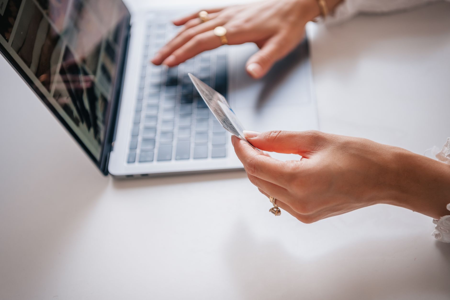 A woman types on a laptop at a clean desk while filling out an online credit freeze form.