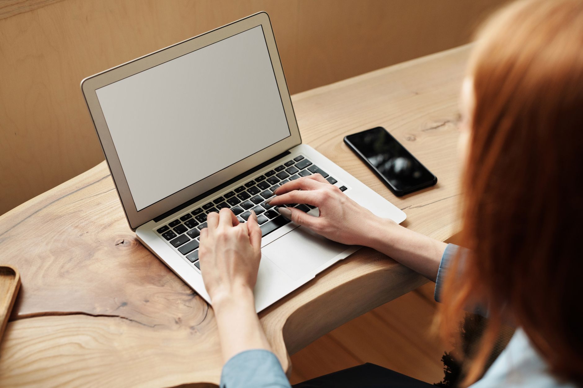 A person looking closely at a photo on a laptop screen while holding a magnifying glass