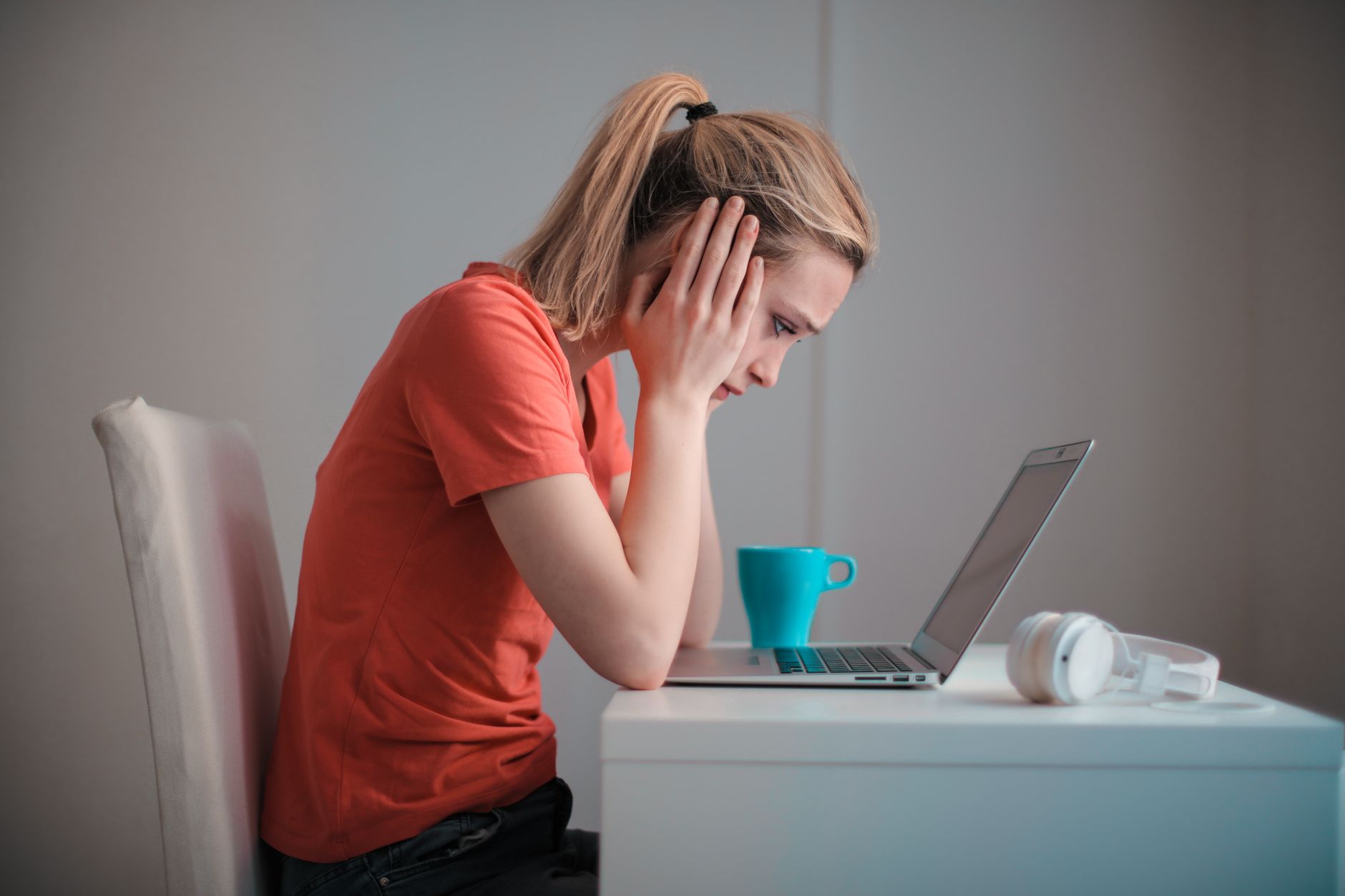 A person looks at a laptop screen with a concerned expression while reading an email inbox.
