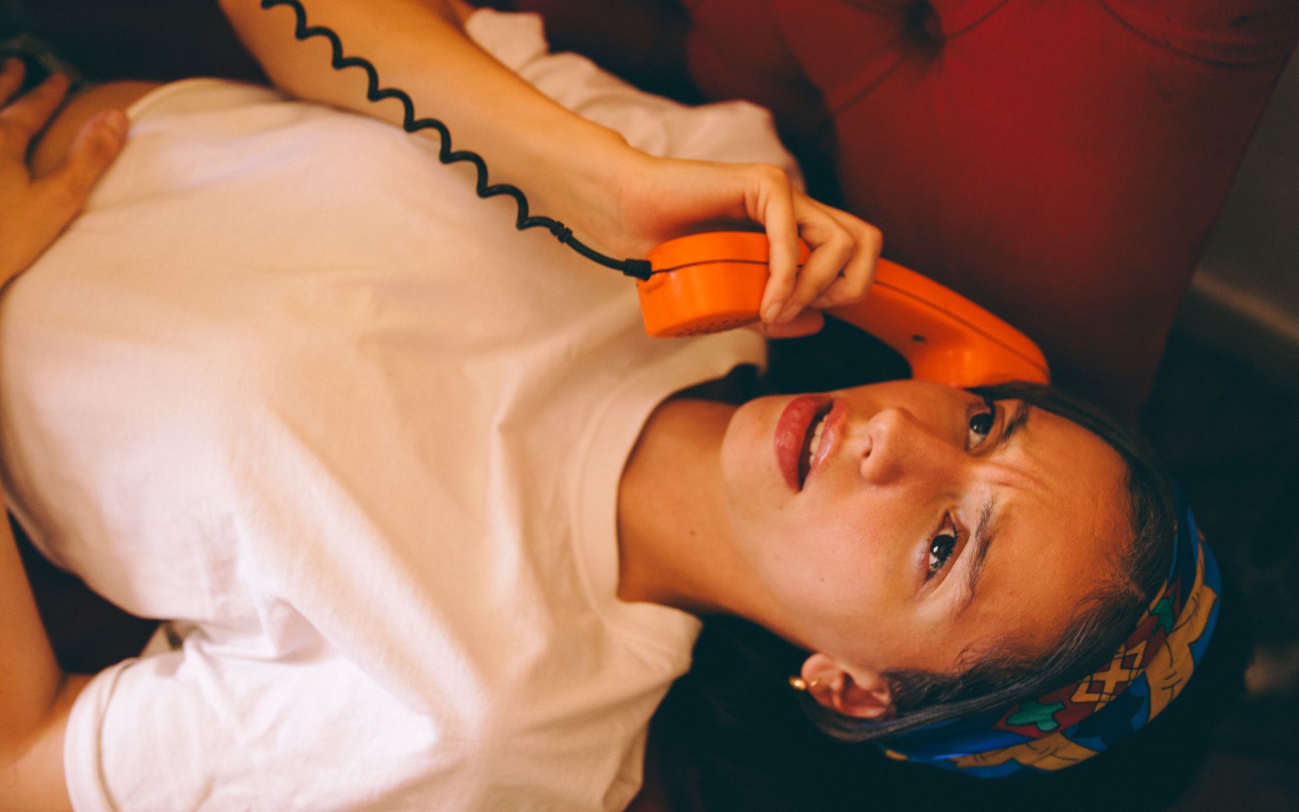 A woman in a living room holds her phone with a worried hand over her mouth, hearing alarming news
